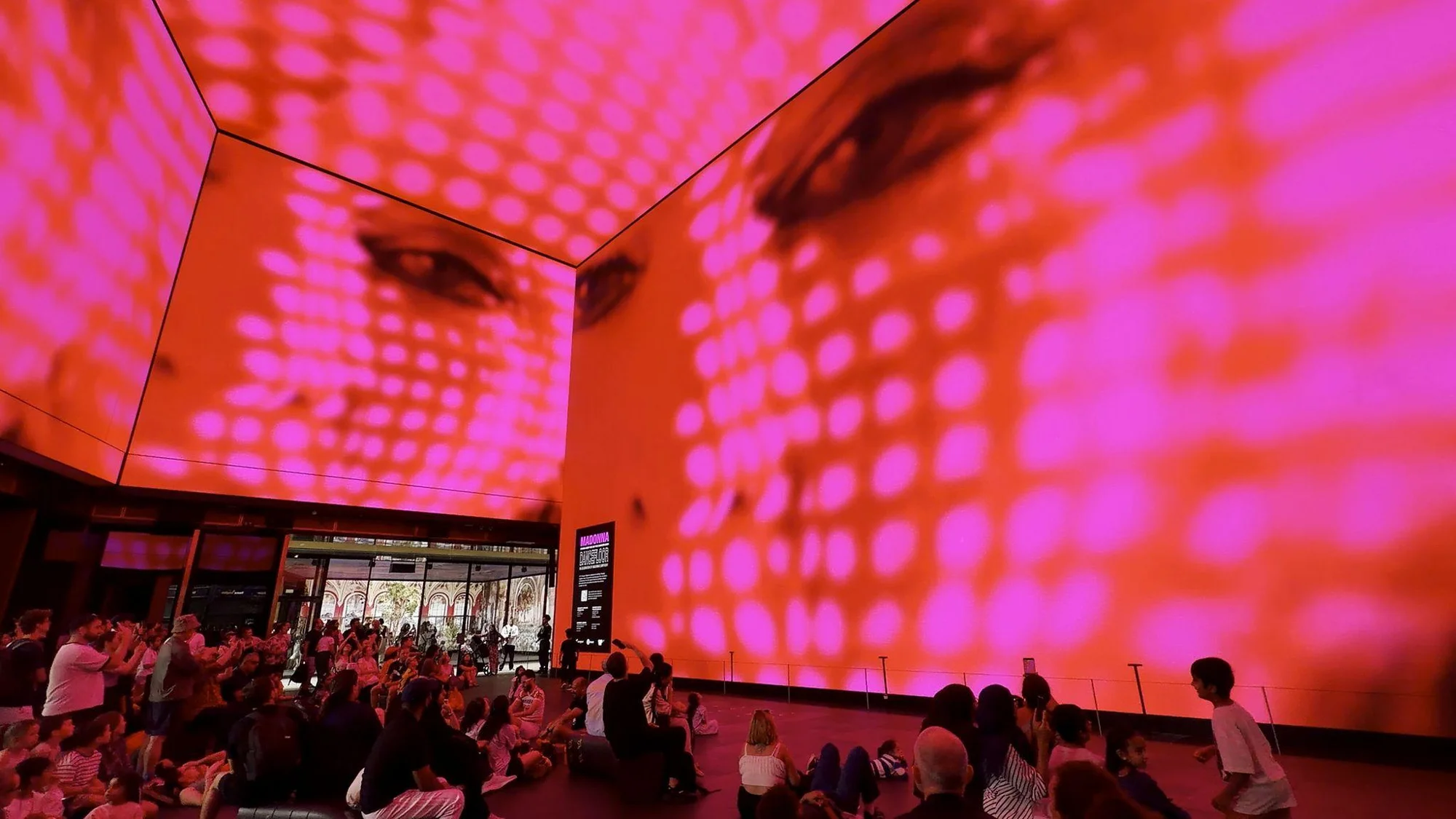Visitors surrounded by vivid pink Madonna visuals.