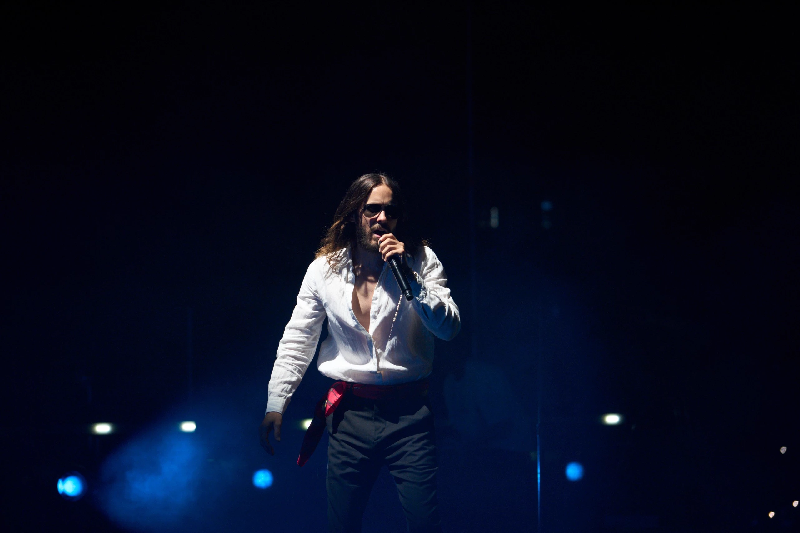 Jared Leto singing in a pool of blue light during the 2025 Central Asia tour