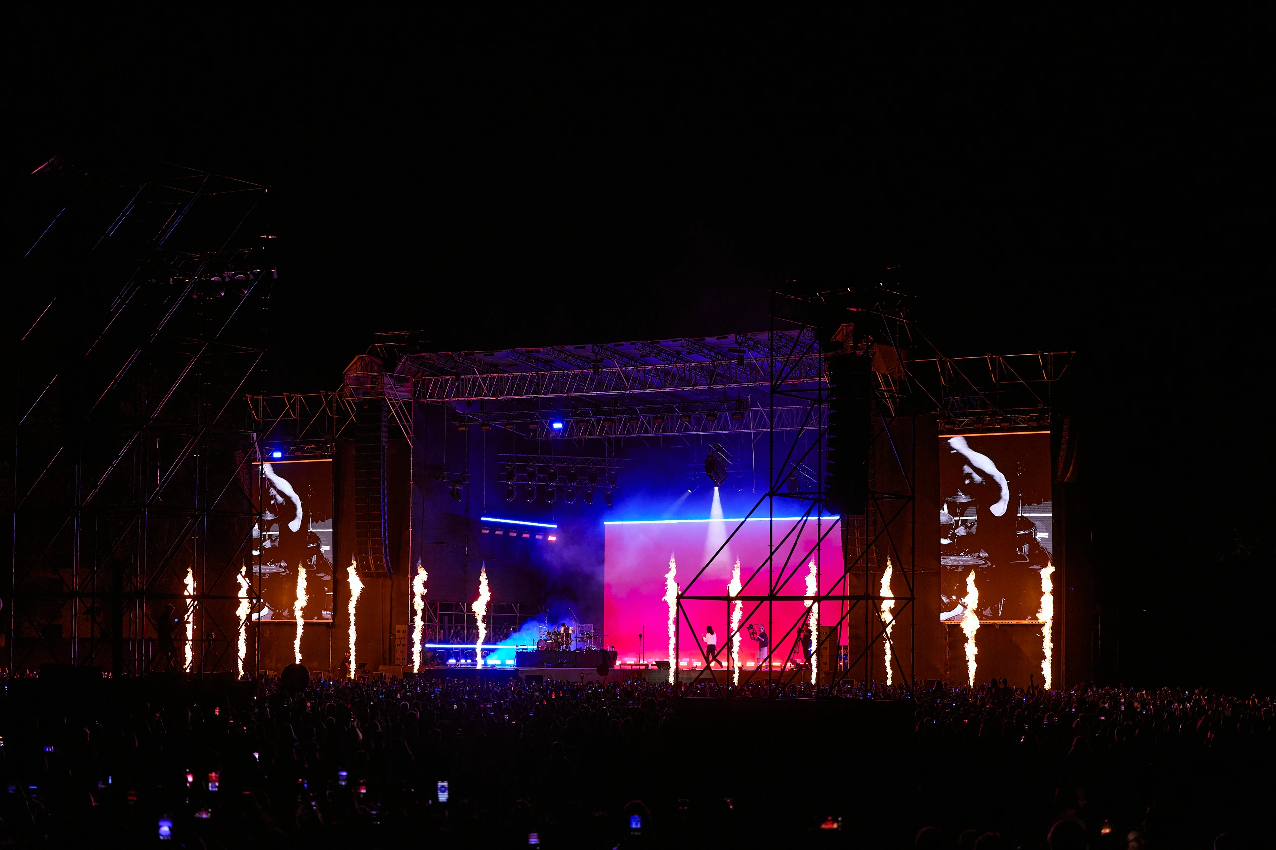 Thirty Seconds to Mars performing beneath blue and pink stage lights and columns of fire
