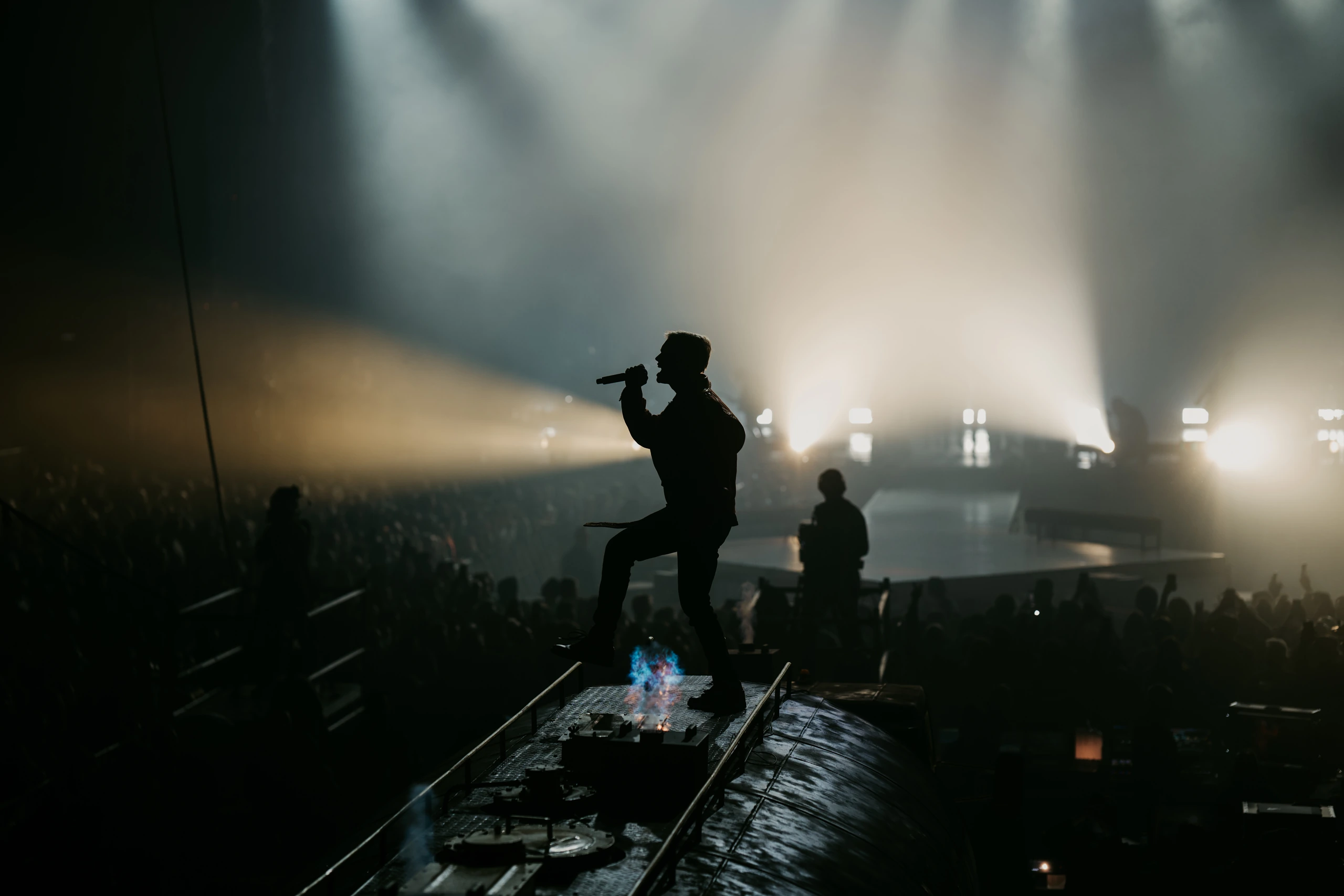 A singer silhouetted against white stage lighting on top of the tanker